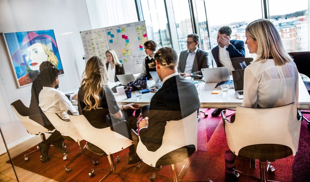 Bild på människor som sitter runt ett bord och har ett möte