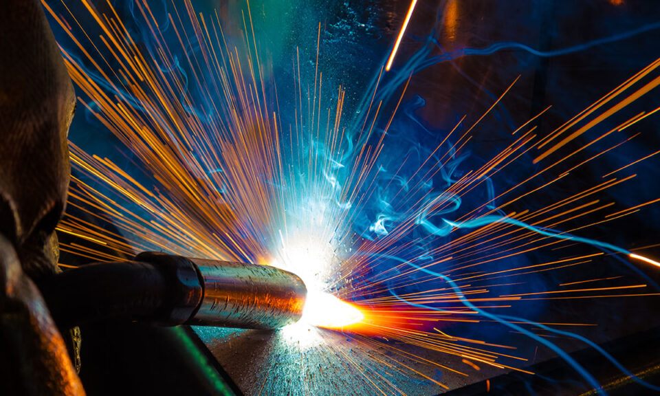 Närbild av svetsning med starka gnistor och blå rök