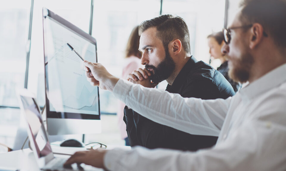 Bild på två män som arbetar framför en datorskärm