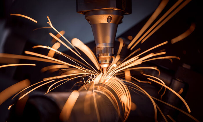 Bild på industrilaser som skär metallrör med gnistor i hög hastighet