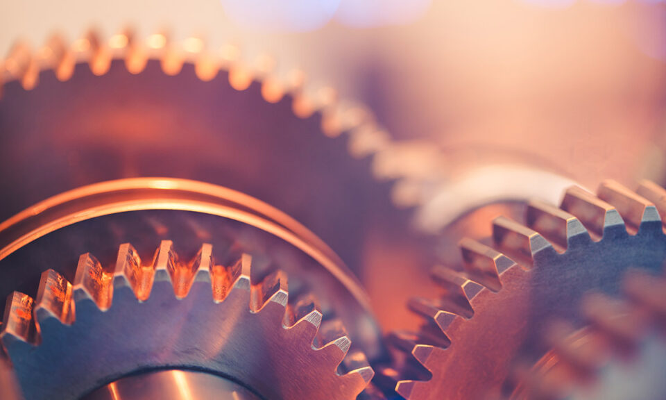 Närbild på samverkande metallkugghjul i varm industriell belysning