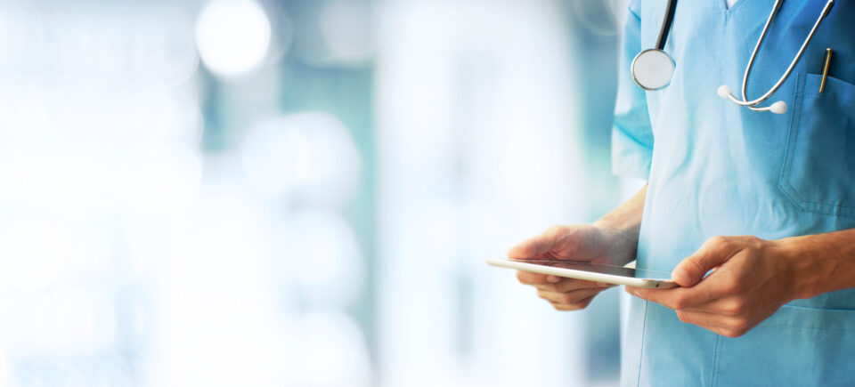 Bild på vårdpersonal som använder digital journal på surfplatta i modern sjukhusmiljö