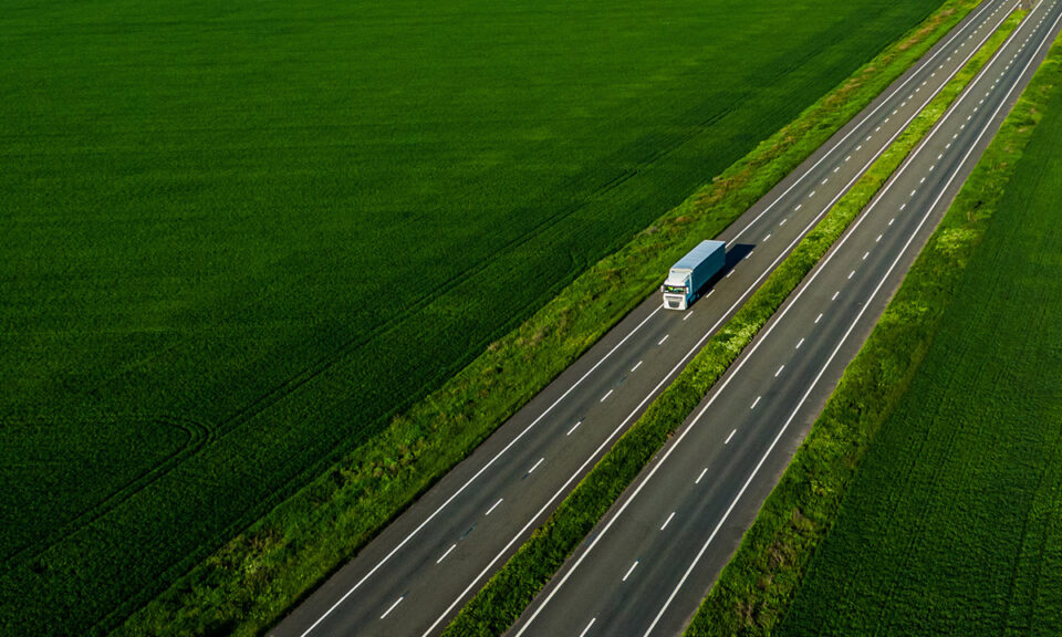 Flygfoto av lastbil på motorväg genom gröna jordbrukslandskap