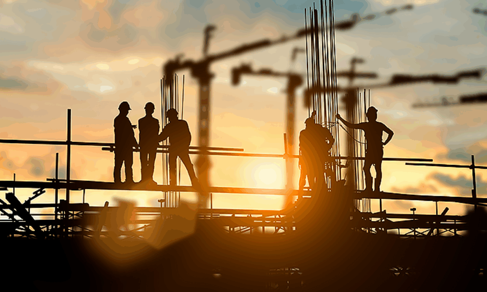 Människor arbetar på en byggnadsställning i solnedgången.